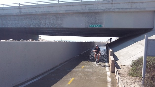 The tide has temporarily flooded the bike path under the Pacific Coast Highway.